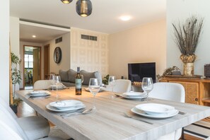 A dining area with a long table set for four, a bottle of wine, and a television in the background. - Funchal Frui Vita by Atlantic Holiday (Funchal)