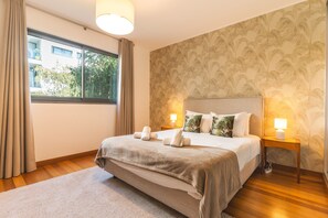 A hotel room with a bed, two bedside lamps, a window with curtains, and a patterned wallpaper. - Funchal Frui Vita by Atlantic Holiday (Funchal)