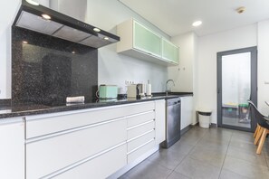 A modern kitchen with white cabinetry, a black countertop, and a dishwasher. - Funchal Frui Vita by Atlantic Holiday (Funchal)