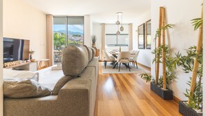 Un salon moderne avec un canapé, un coin repas et de grandes fenêtres.