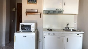 A compact kitchen with a microwave, a small refrigerator, a sink, and a stove. - Nikos Studio 2 in Gialiskari (Ikaria)