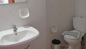 A bathroom with a sink, toilet, and a trash bin. - Nikos Studio 2 in Gialiskari (Ikaria)