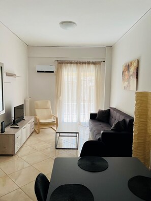 Un salon moderne avec un canapé, une table basse, un téléviseur et un fauteuil.