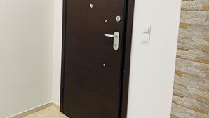 A closed dark wooden door with a handle and a lock, white wall, and a stone-textured wall to the right. - Piraeus 3 in Piraeus (Piraeus)