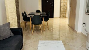 A modern living room with a dark sofa, a marble coffee table, and a dining area with a table and chairs. - Piraeus 3 in Piraeus (Piraeus)