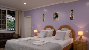 A bedroom with a large bed, two bedside tables with lamps, a sofa, and artwork on the wall. - Vila do Largo B by Homie (São Vicente)