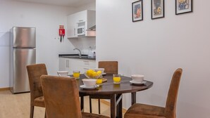 Una cucina moderna con pensili bianchi, un frigorifero in acciaio inossidabile e un'area pranzo con un tavolo rotondo e sedie marroni.