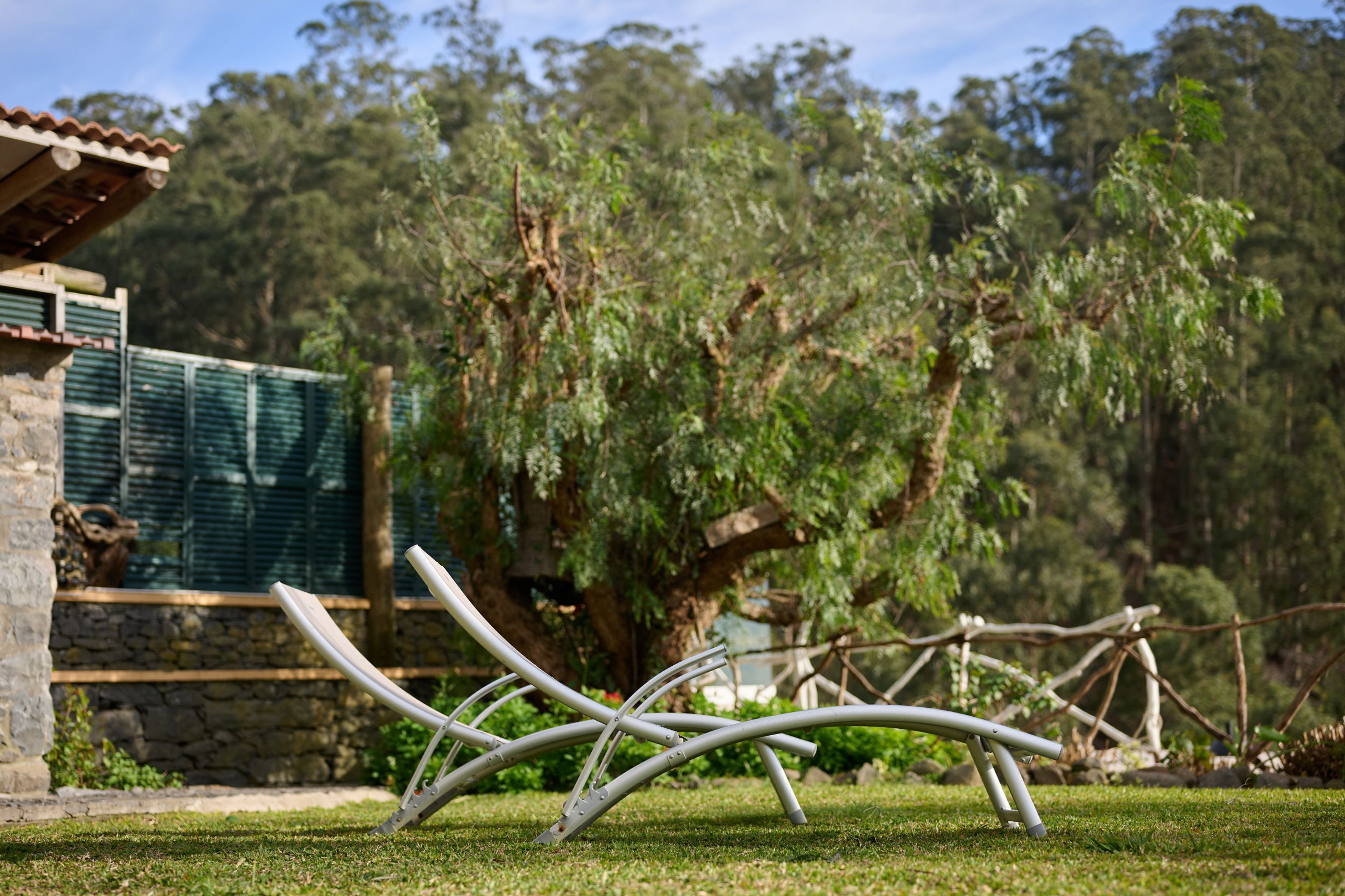 Ein Garten mit Steinmauer, Metallskulptur und Baum.