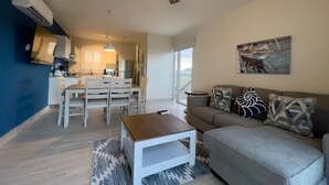 Uma sala de estar moderna com sofá, mesa de centro e área de jantar com cadeiras e mesa.