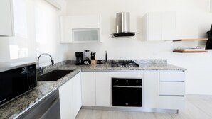Una cucina moderna con mobili bianchi, piano cottura integrato, microonde e lavastoviglie.