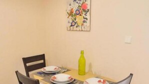 Een eettafel met vier stoelen, een gele fles en bloemkunst op de muur.
