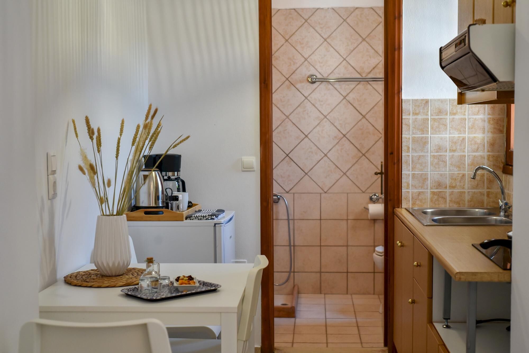 A compact kitchen with a sink, a coffee machine, and a small dining area with a table and chairs.