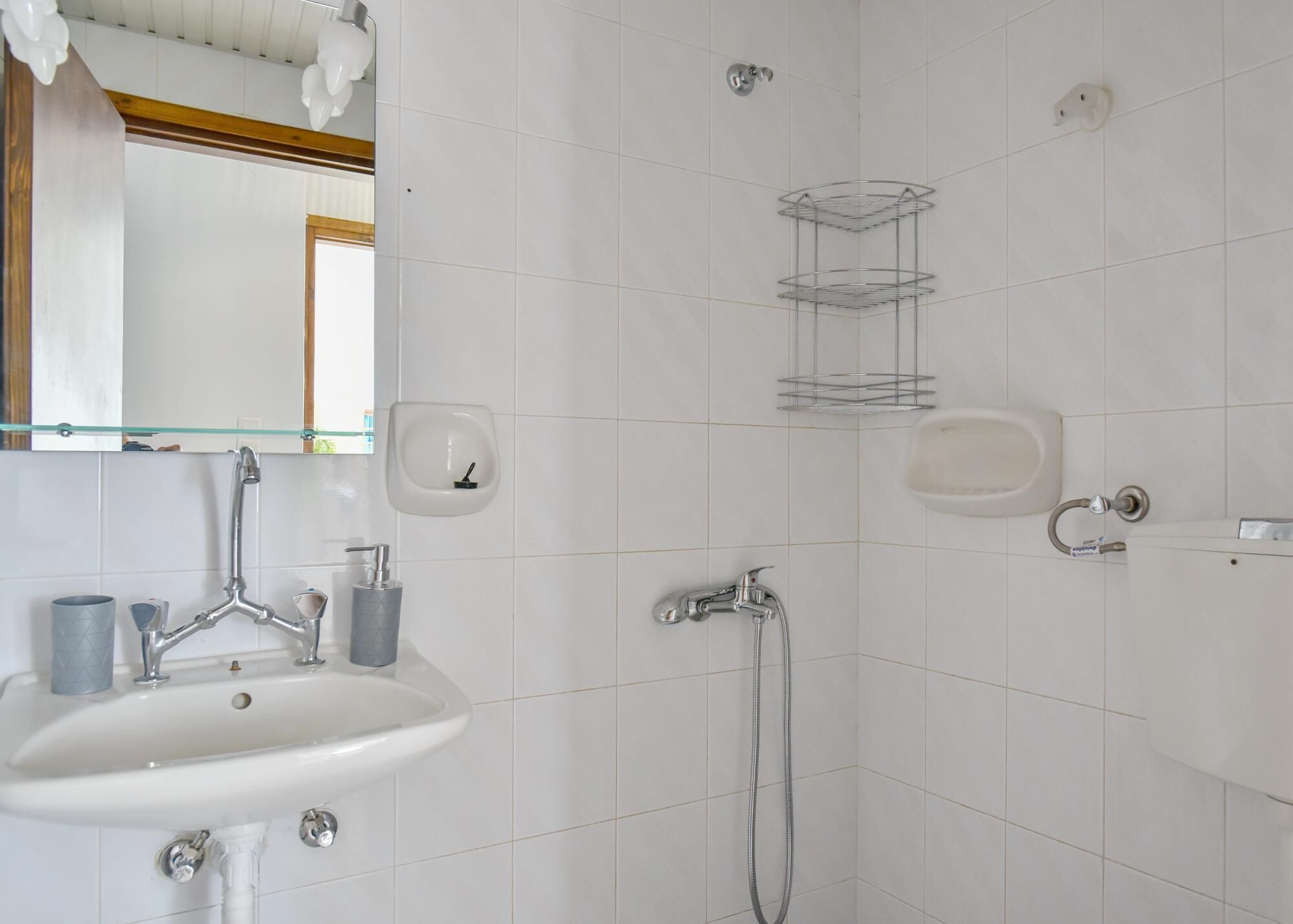 A bathroom with a sink, mirror, towel rack, and shower.
