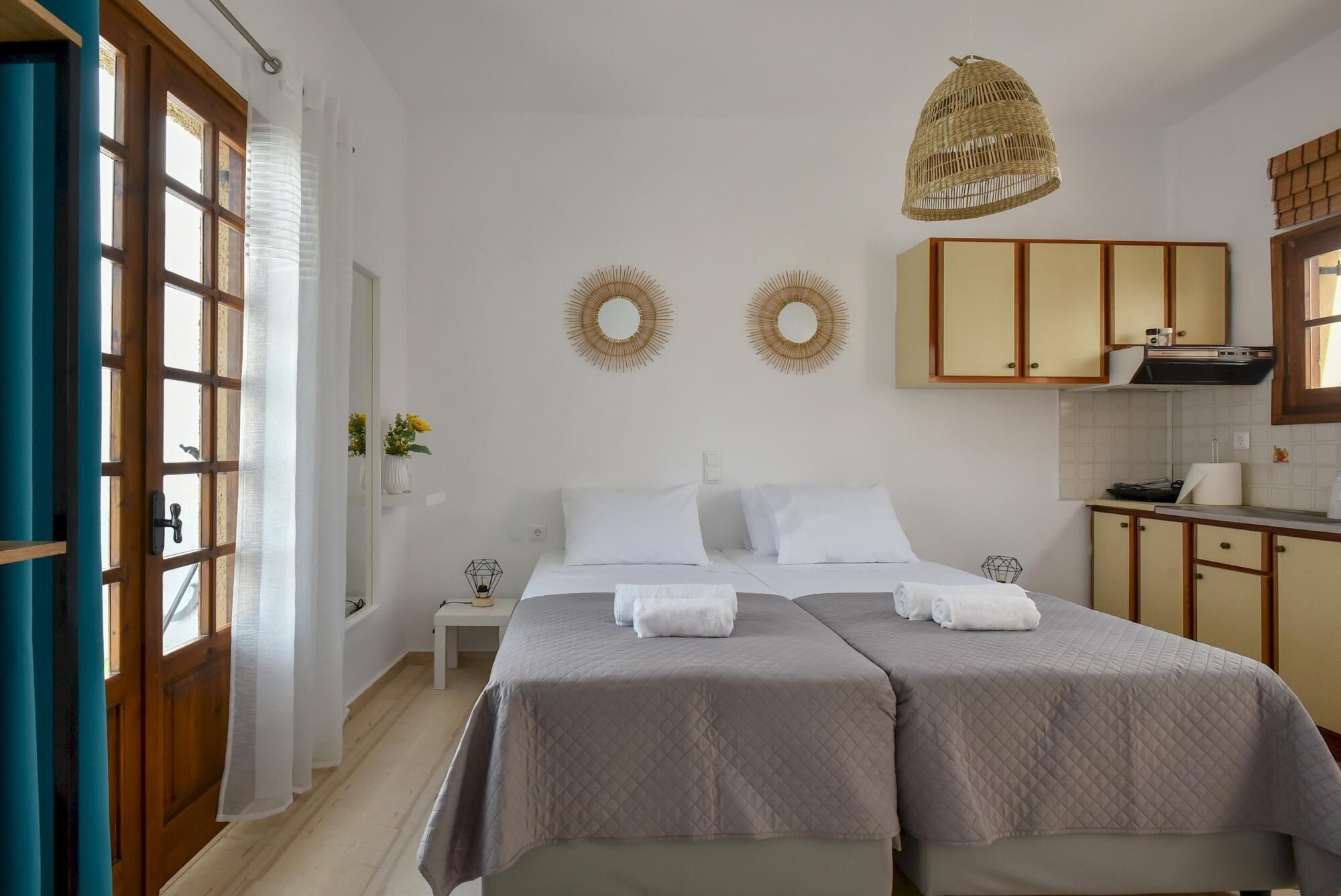 Een slaapkamer met twee bedden, een kitchenette en uitzicht.