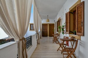A balcony with wooden furniture and curtains, a wooden door, and a hanging plant. - Eva Studios 8 in Agia Pelagia (Malevizi)