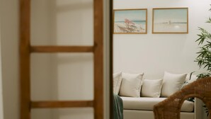 Une pièce avec un canapé, une échelle en bois et deux tableaux encadrés accrochés au mur.