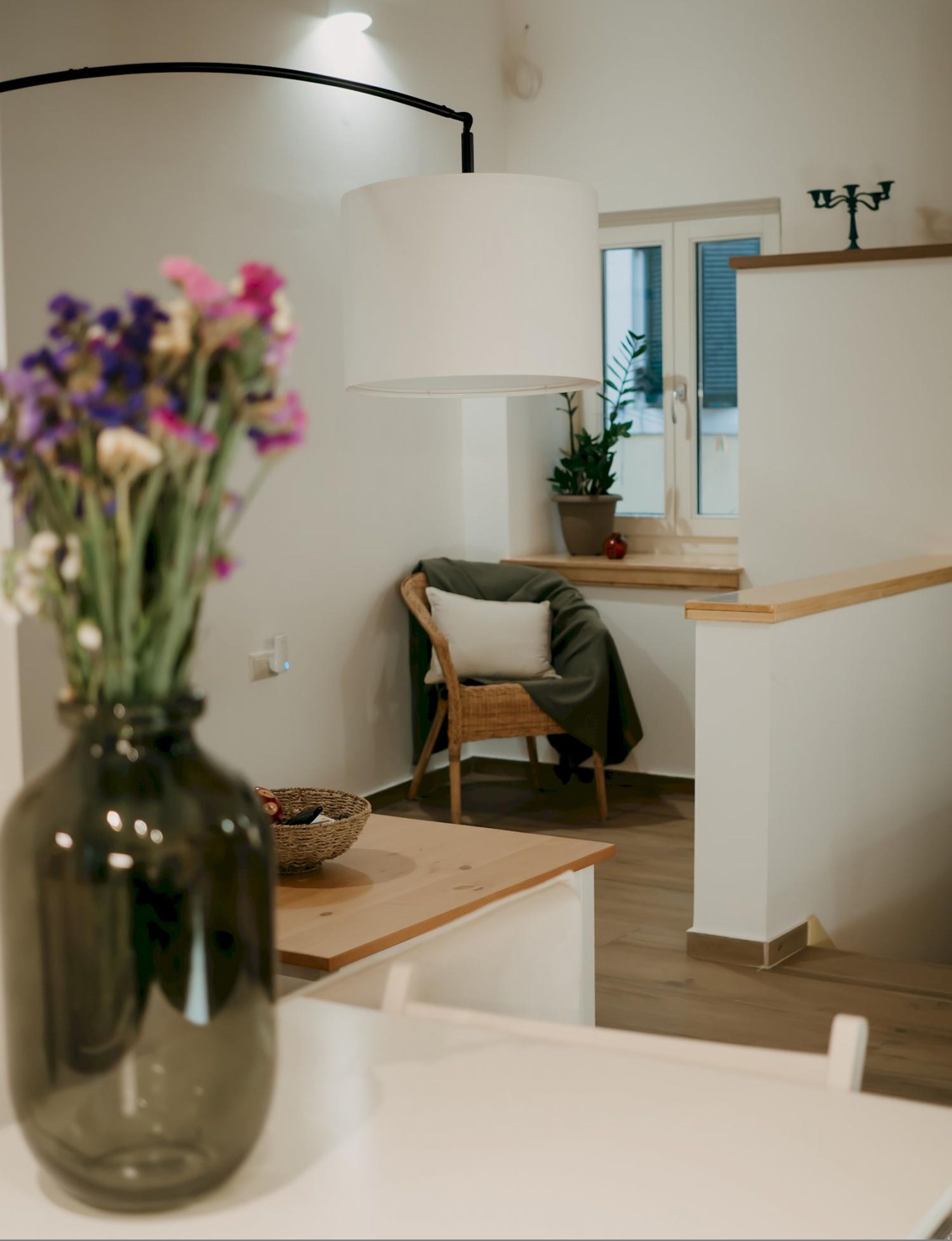 En moderne stue med et træbord, en fletkurv og en vase med blomster.