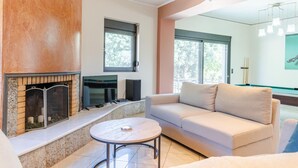 Ein modernes Wohnzimmer mit Kamin, Billardtisch und einer Couch.