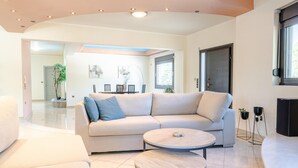 Ein modernes Wohnzimmer mit einem beigefarbenen Sofa, zwei runden Couchtischen und einem großen Fenster.