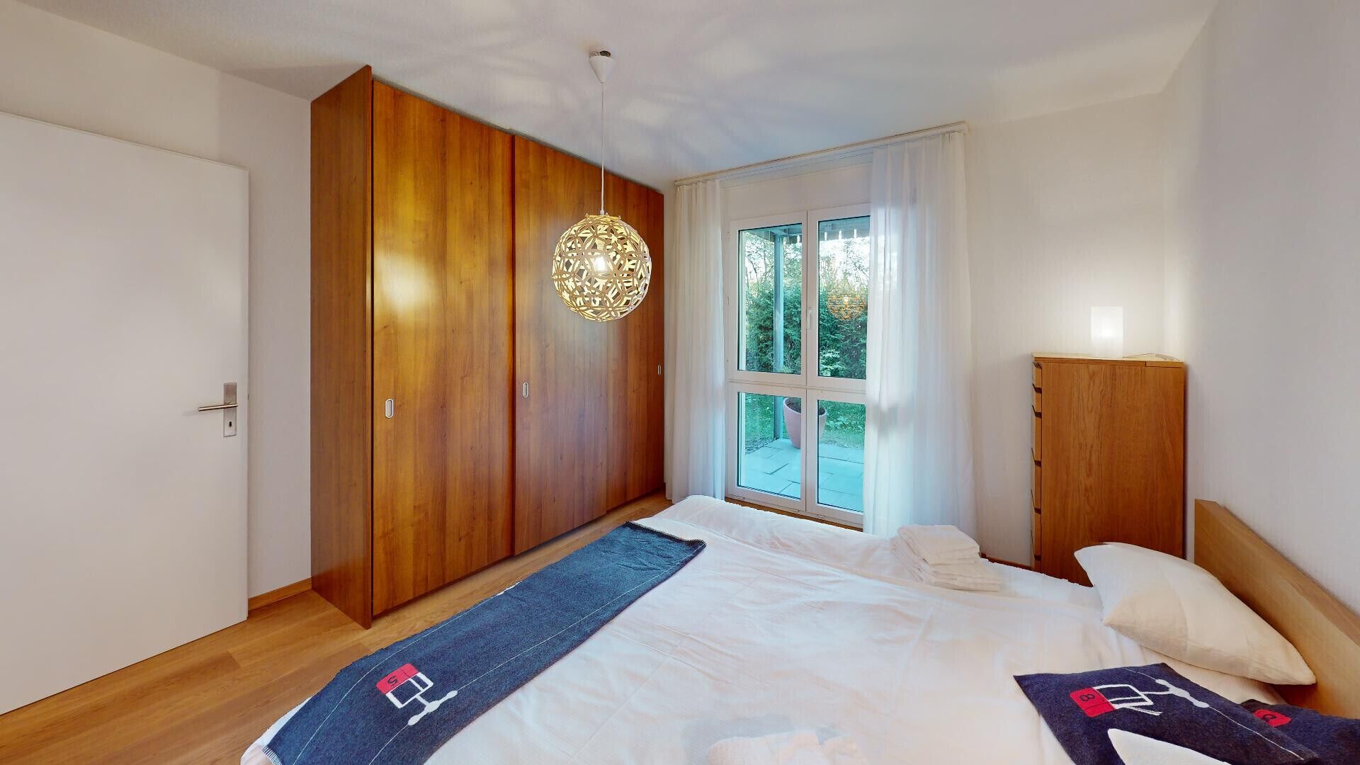 Une chambre à coucher avec un lit, une armoire en bois et une fenêtre donnant sur un paysage verdoyant.