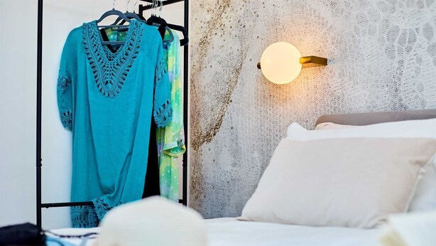 A bedroom with a bed, a wall-mounted light, and a clothing rack with a blue garment. - Exquisite Villa by Dominium - Old city (Dubrovnik)