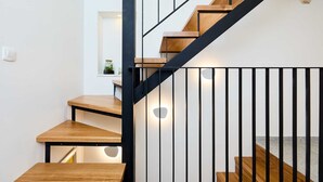 A staircase with wooden steps and black metal railings, leading to a landing with a small table and a potted plant. - Exquisite Villa by Dominium - Old city (Dubrovnik)