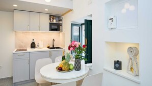 A modern kitchen with white cabinets, a built-in microwave, and a dining area with a table set for two. - Exquisite Villa by Dominium - Old city (Dubrovnik)
