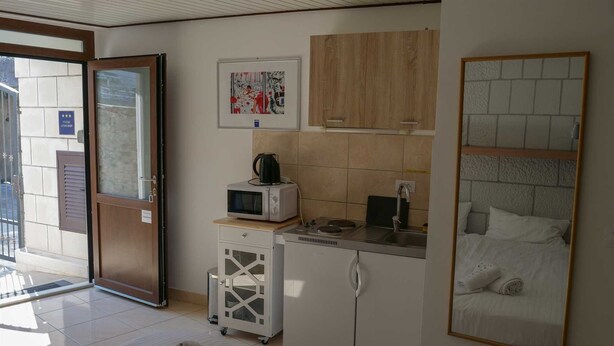 A compact hotel room with a kitchenette, a bed, and a bathroom. - DUBROVNIK HAUS suites Standard studio apartment (Dubrovnik)