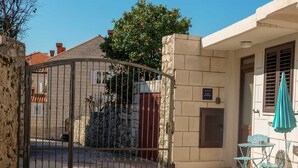 A gated entrance to a building with a stone wall, a metal gate, and a sign indicating a studio apartment. - DUBROVNIK HAUS suites Standard studio apartment (Dubrovnik)