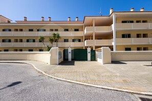 A multi-story hotel with a central entrance, balconies, and a paved driveway.