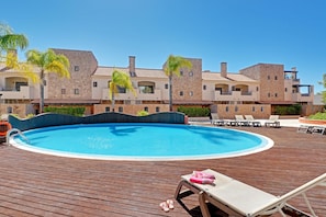 A swimming pool surrounded by lounge chairs and a wooden deck. - Victoria Garden in Vilamoura (Loulé)