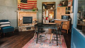 Un intérieur rustique avec une cheminée, une table à manger en bois et des chaises.