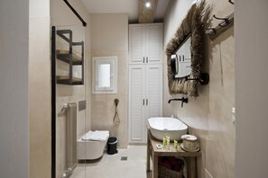A bathroom with a glass shower enclosure, a white bathtub, a sink with toiletries, and a large mirror with a decorative frame.