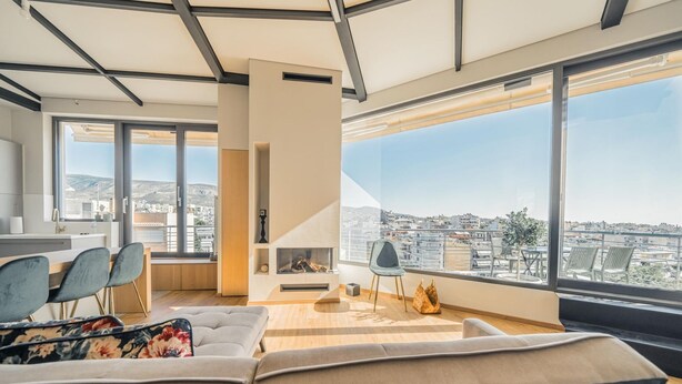 Ein modernes Wohnzimmer mit großem Fenster, einer Couch, einem Kamin und einem Essbereich.