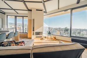 Un salon moderne doté d’une grande fenêtre, d’un canapé, d’une cheminée et d’un coin repas.