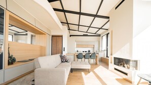 Ein modernes Wohnzimmer mit einer Couch, einem Kamin und einer Küche im Hintergrund.