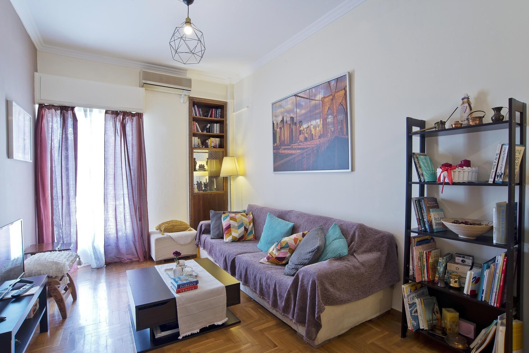 Ein gemütliches Wohnzimmer mit einer Couch, einem Couchtisch, einem Bücherregal und einem Bild an der Wand.
