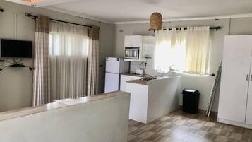 Een compacte keuken met een magnetron, fornuis en spoelbak. Er is een klein eiland met een spoelbak en een televisie aan de muur bevestigd.