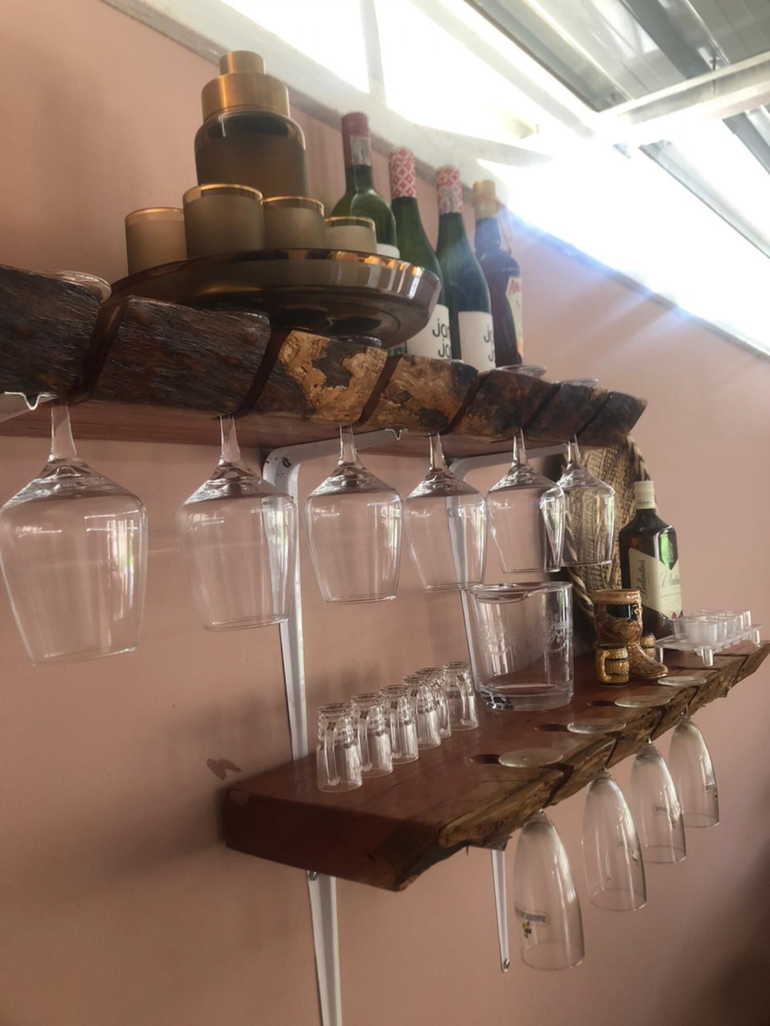 Una botellera de madera con copas y botellas de vino al fondo.