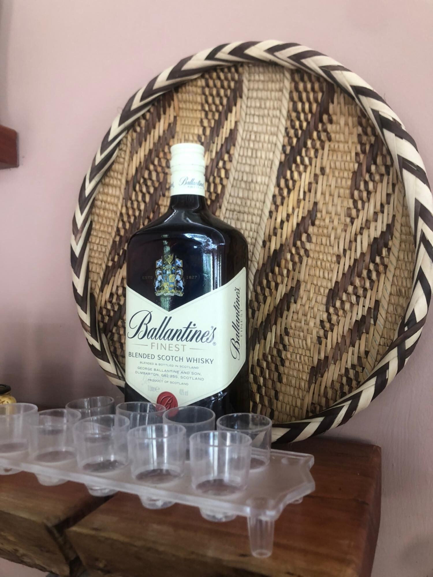 A bottle of Ballantine's Finest Blended Scotch Whisky on a wooden surface with a woven basket in the background.