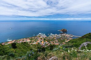 A coastal town with a mix of residential and commercial buildings, a prominent rocky outcrop, and a clear view of the sea. - Chalet do Monte Porto Moniz by Madeira Sun Travel (Porto Moniz)