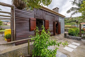 A rustic wooden house with a balcony, a stone pathway, and a small garden area. - Chalet do Monte Porto Moniz by Madeira Sun Travel (Porto Moniz)