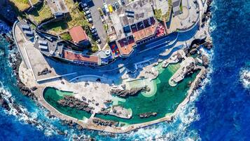 An aerial view of a coastal resort with a marina, swimming areas, and a large building with a red roof.
