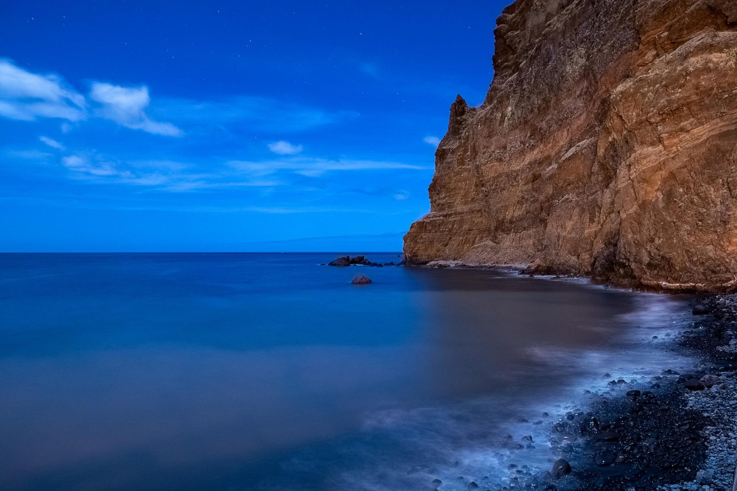 A coastal landscape with a cliff and calm sea.
