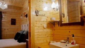Um quarto estilo cabana de madeira, com uma cama, pia e espelho.