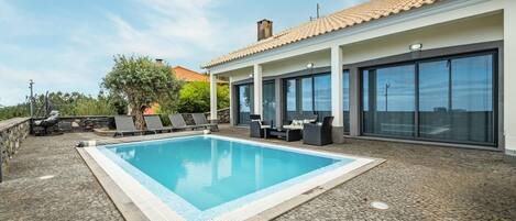 A swimming pool with lounge chairs and a patio area.