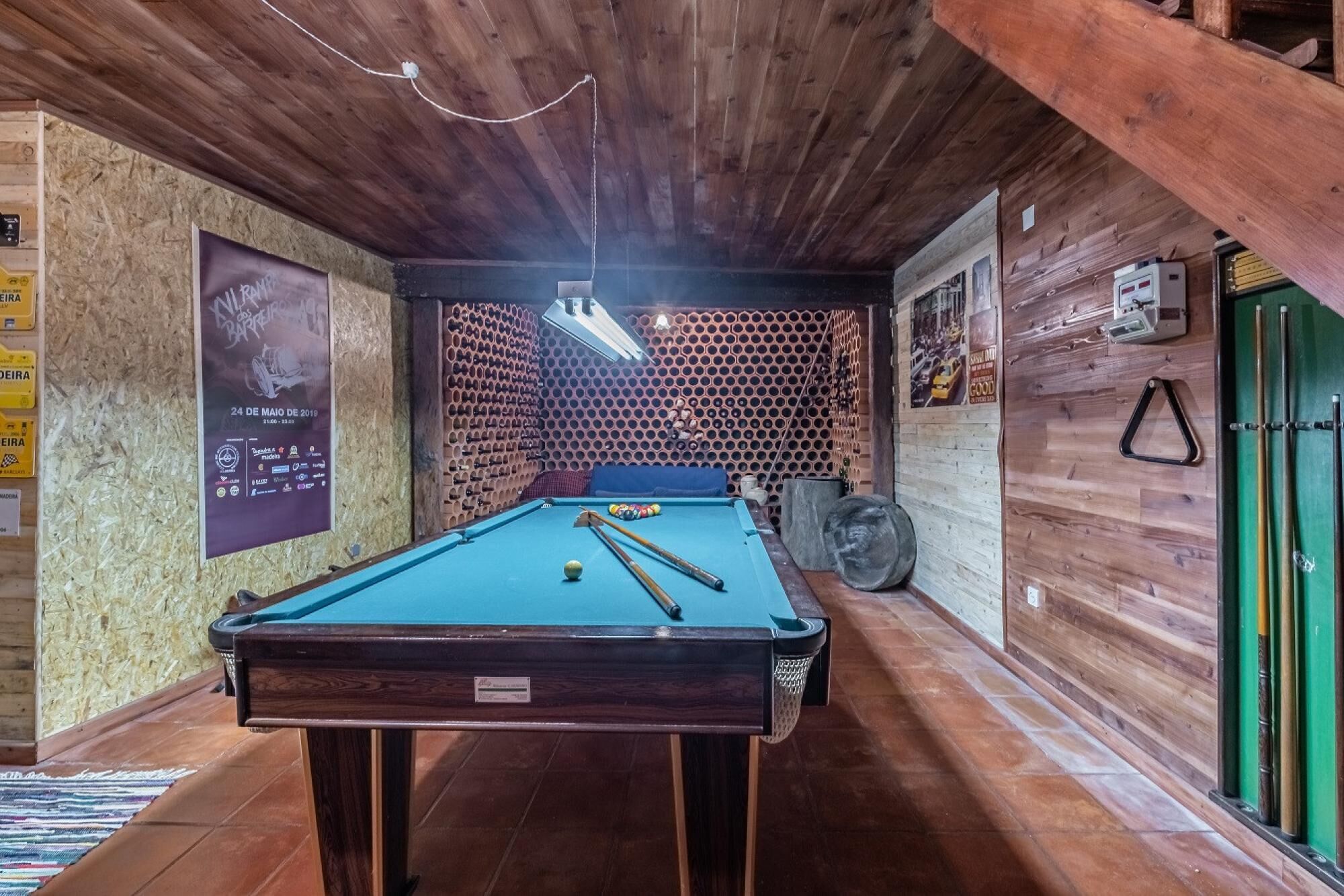 A pool table in a room with wooden walls and a sloped ceiling.