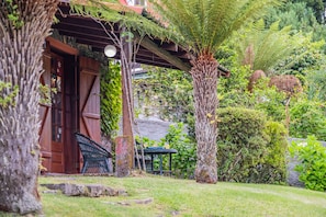 Uma casa de madeira tradicional com varanda coberta, rodeada por vegetação exuberante e um jardim bem cuidado.