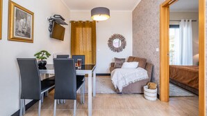 A compact living space with a dining area, a sofa, a bed, and a small bathroom. - Ocean Panorama Apartment 2 by Homie (Calheta)