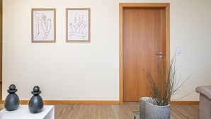 A hallway with two framed line drawings, a wooden door, and a potted plant. - Canhas Residence II by Homie (Ponta do Sol)